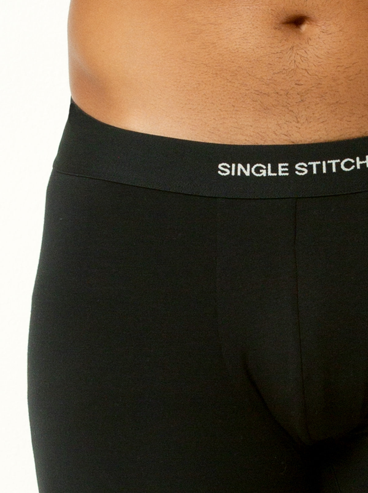 close up shot of male model wearing black colored boxer briefs with single stitch logo on waist band