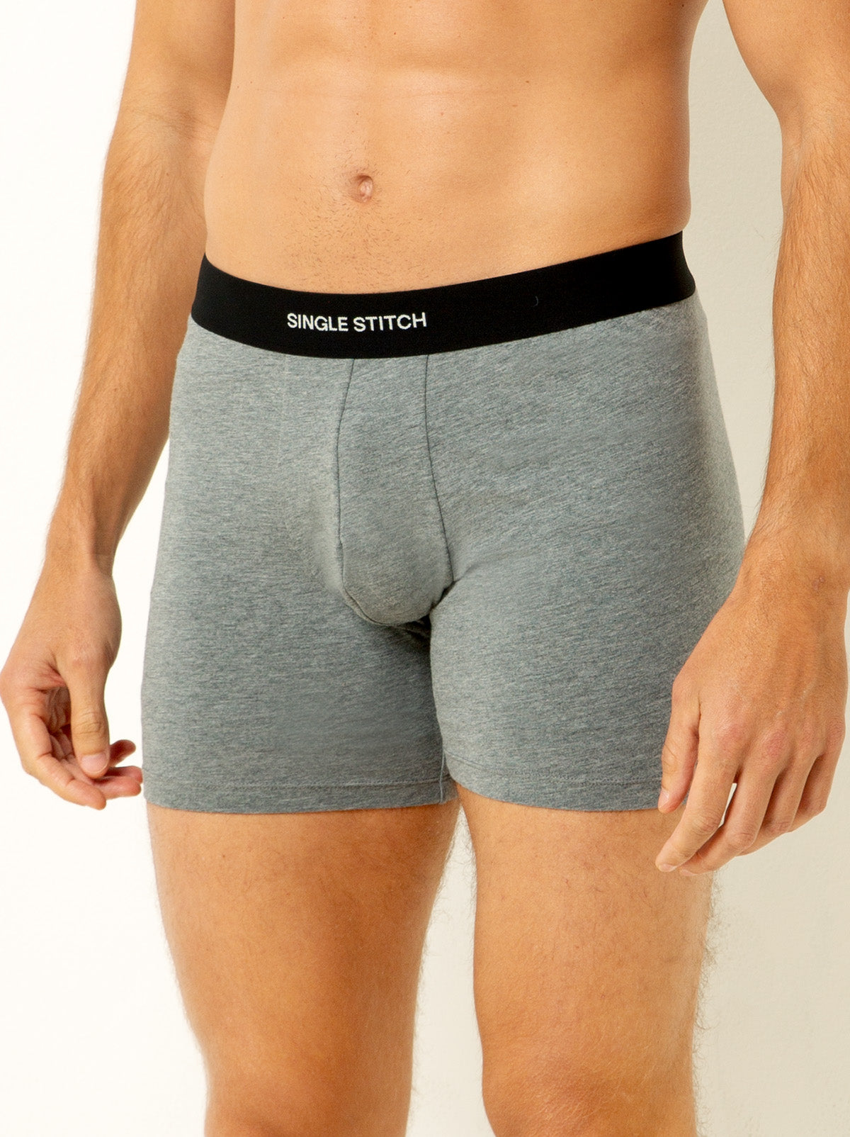 male model wearing heather grey colored boxer briefs with single stitch logo on waist band