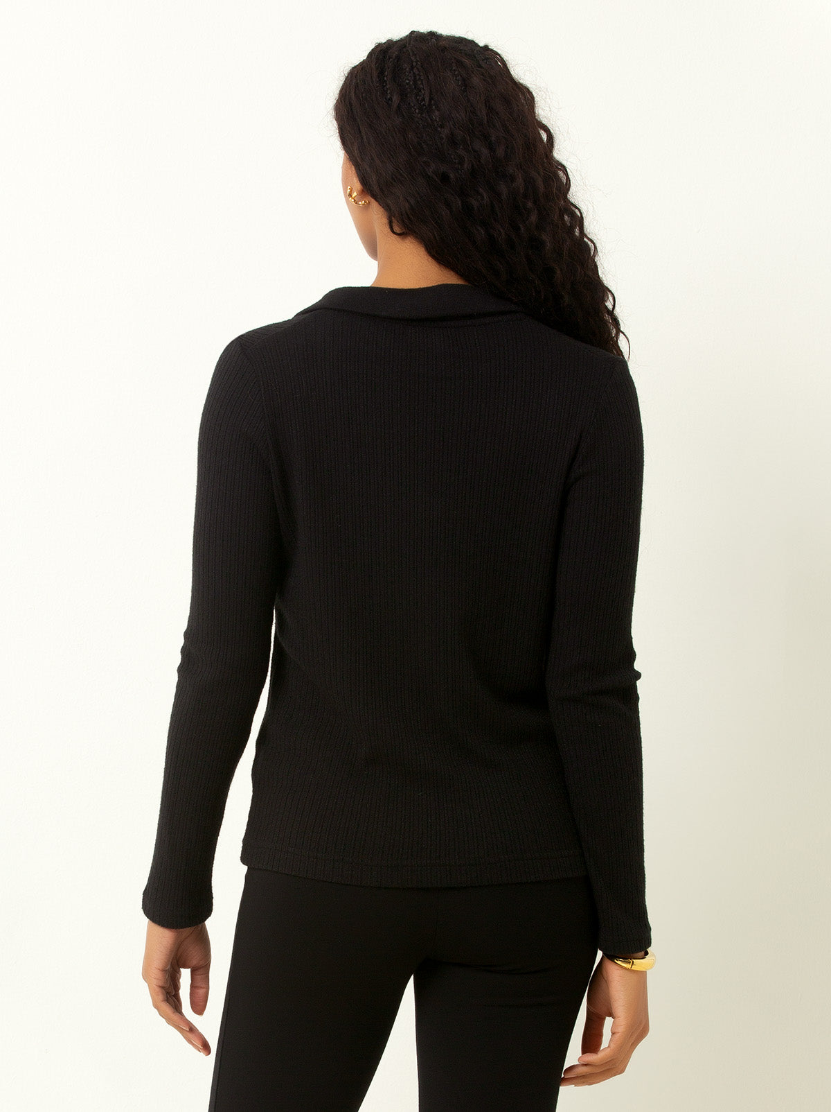 back shot of female model waring a black colored v neck sweater with collar