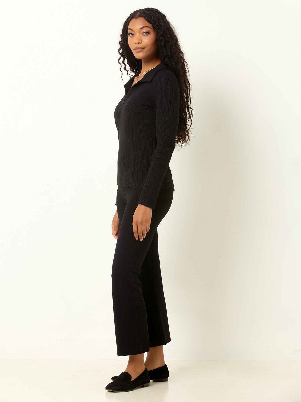 female model waring a black colored v neck sweater with collar and black pant and black shoes