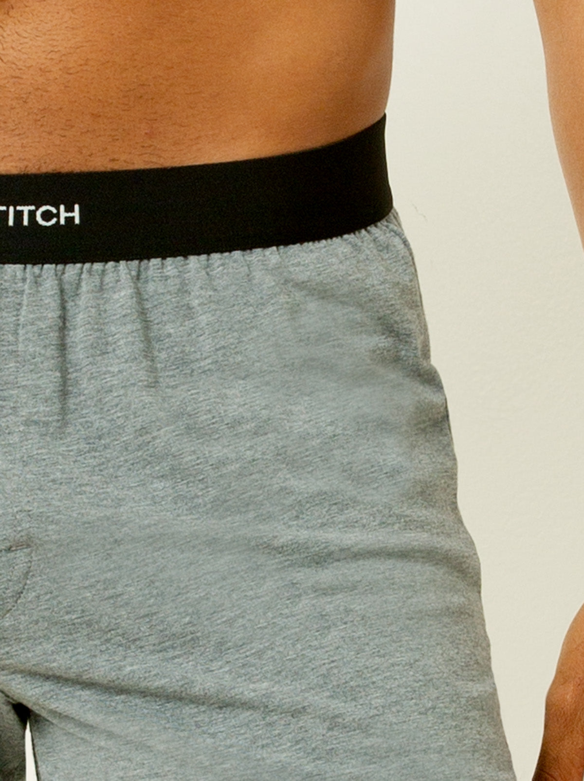 close up shot male model wearing grey colored boxer briefs with single stitch logo on waist band