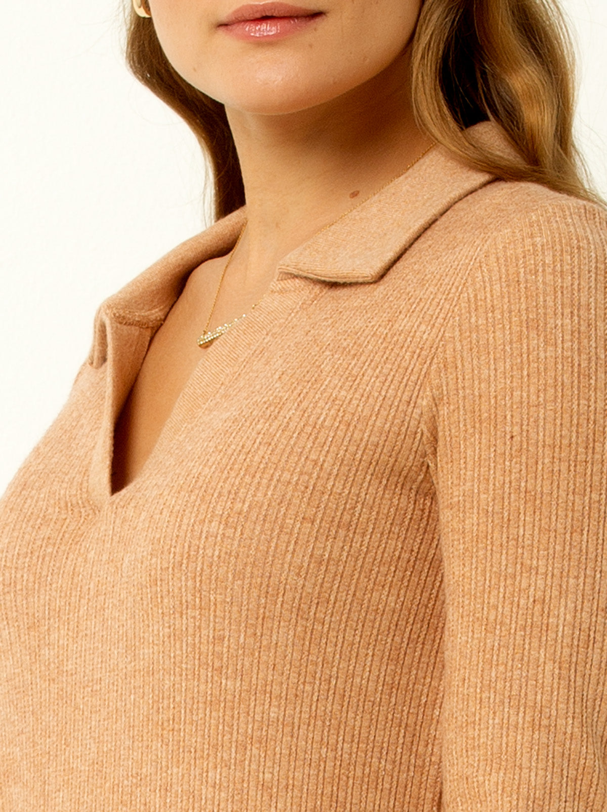 close up shot of female model waring a macaroon colored v neck sweater with collar