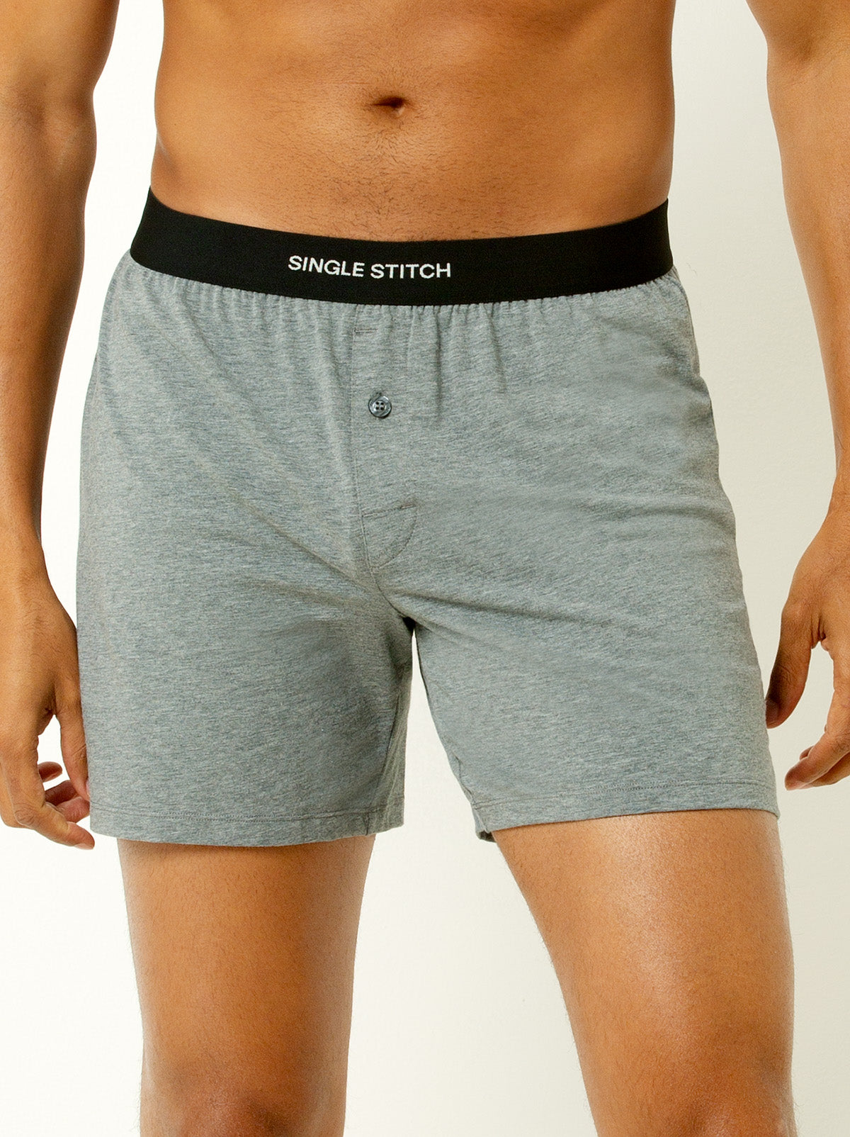 male model wearing heather grey colored briefs with single stitch logo on waist band