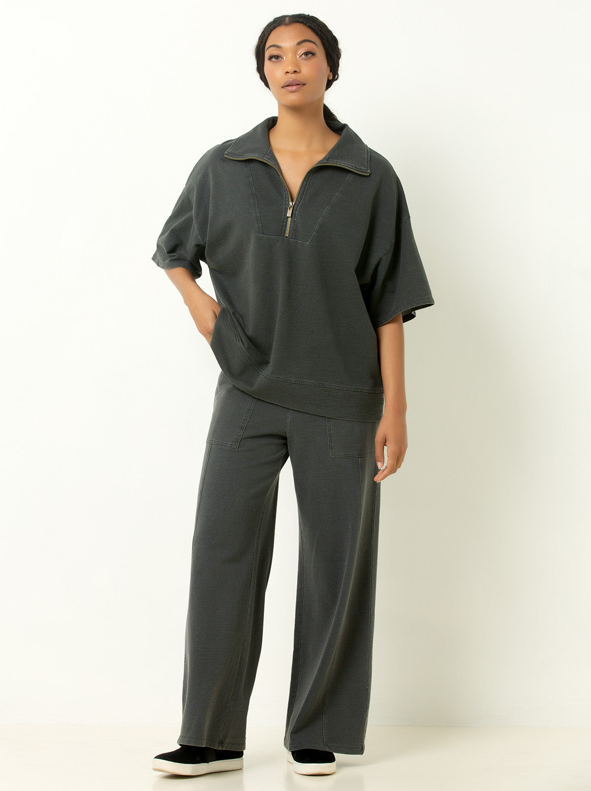 Full body photo of model wearing wide pants and gray 1/4 zip sweatshrit