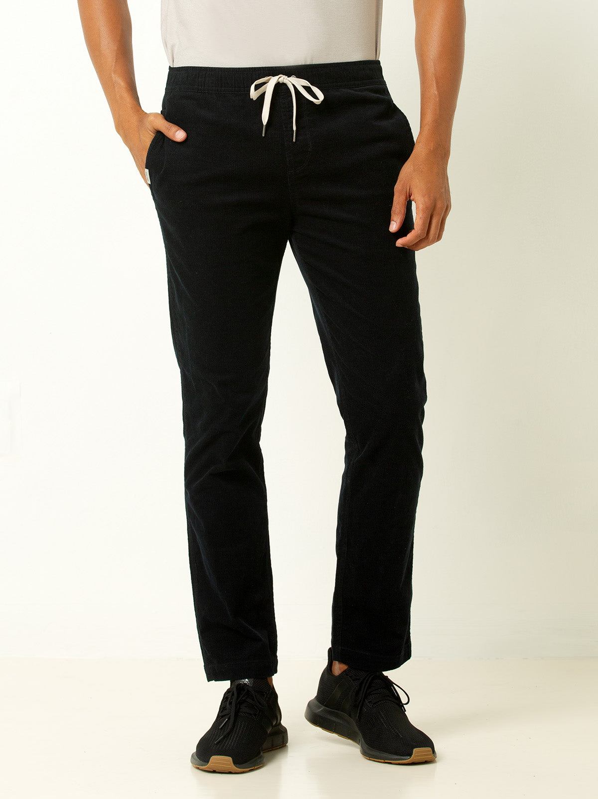 male model image waist down, wearing navy blue corduroy pants with drawstrong - model has hand in pocket