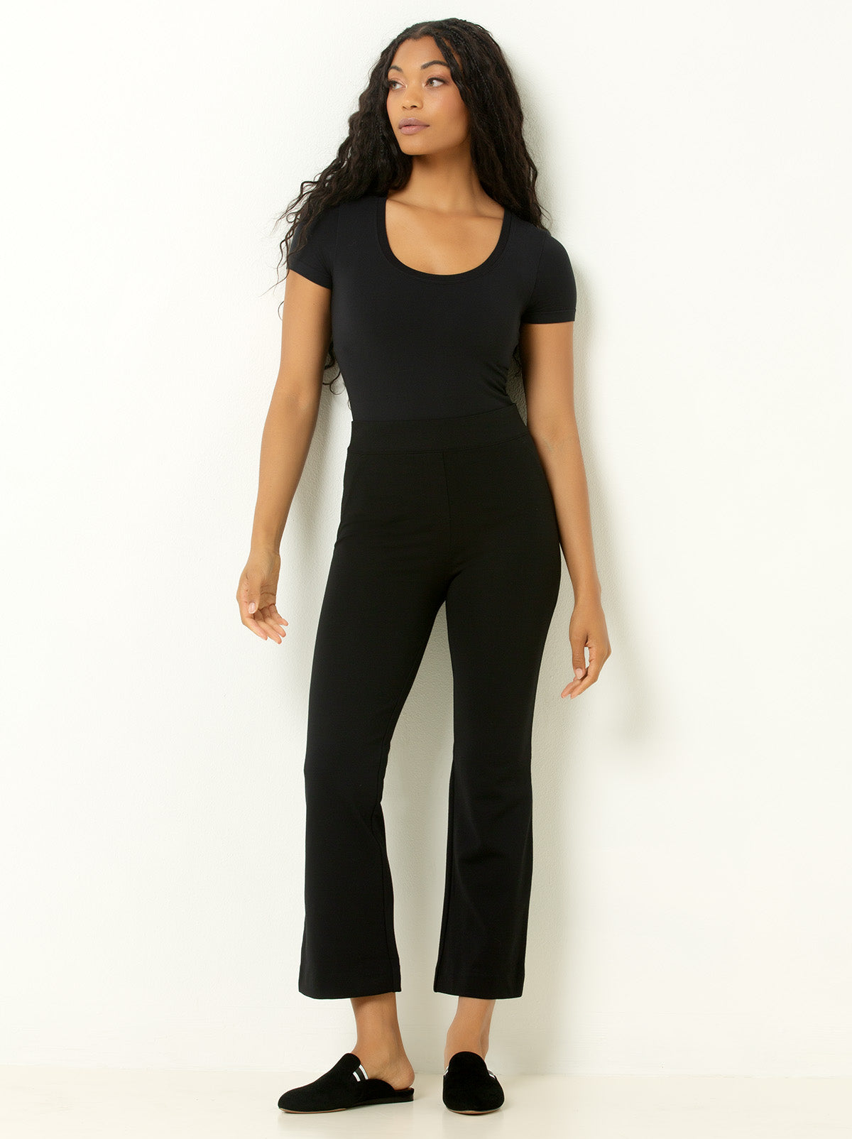 Female model wearing black bodysuit top and cropped black pants