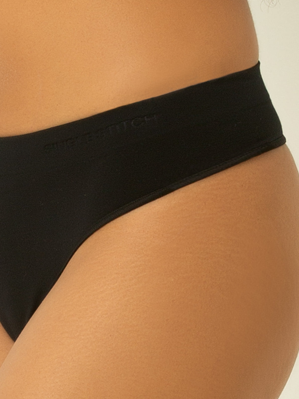 Close up female model wearing black colored underwear with single stitch logo on waist band