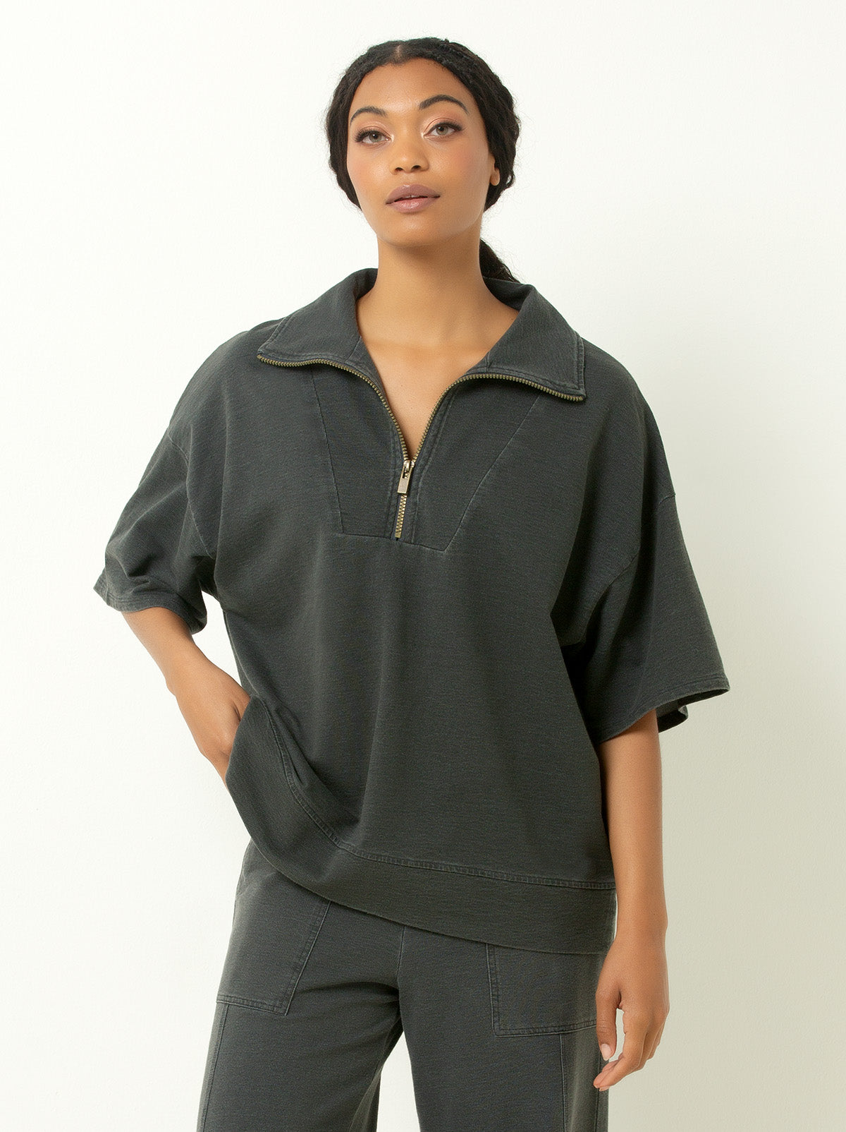 Woman wearing  gray 1/4 zip sweatshirt with elbow length sleeves