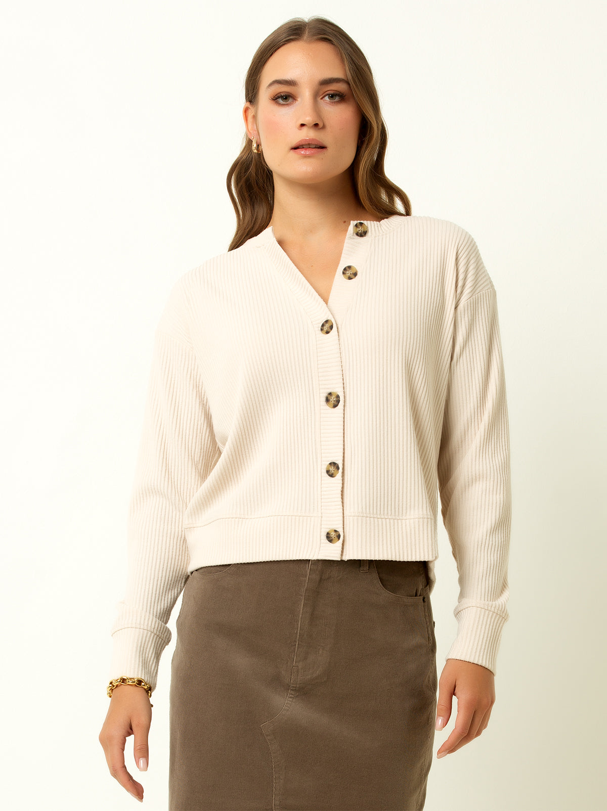 female model wearing a white colored ribbed cardigan sweater with buttons