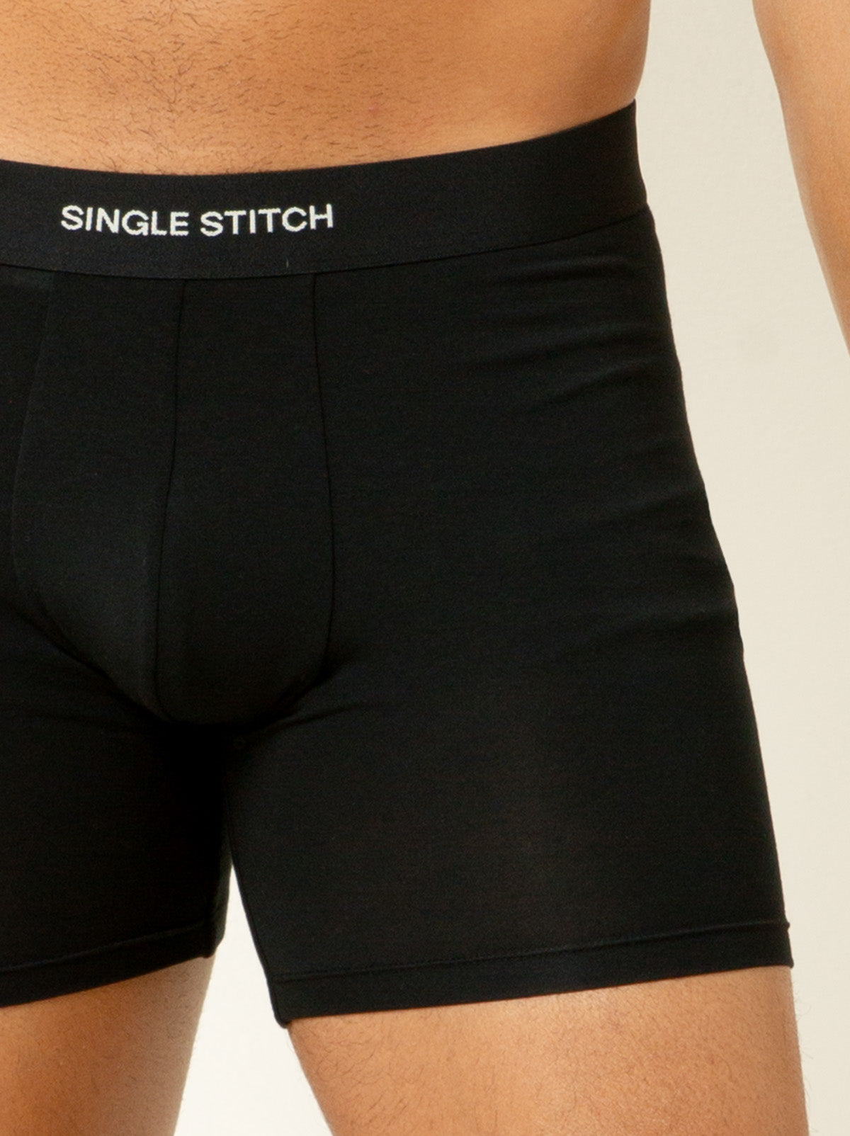 close up shot of male model wearing black colored boxer briefs with single stitch logo on waist band