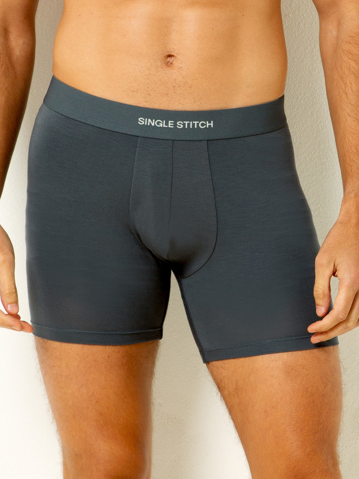 male model wearing grey colored boxer briefs with single stitch logo on waist band