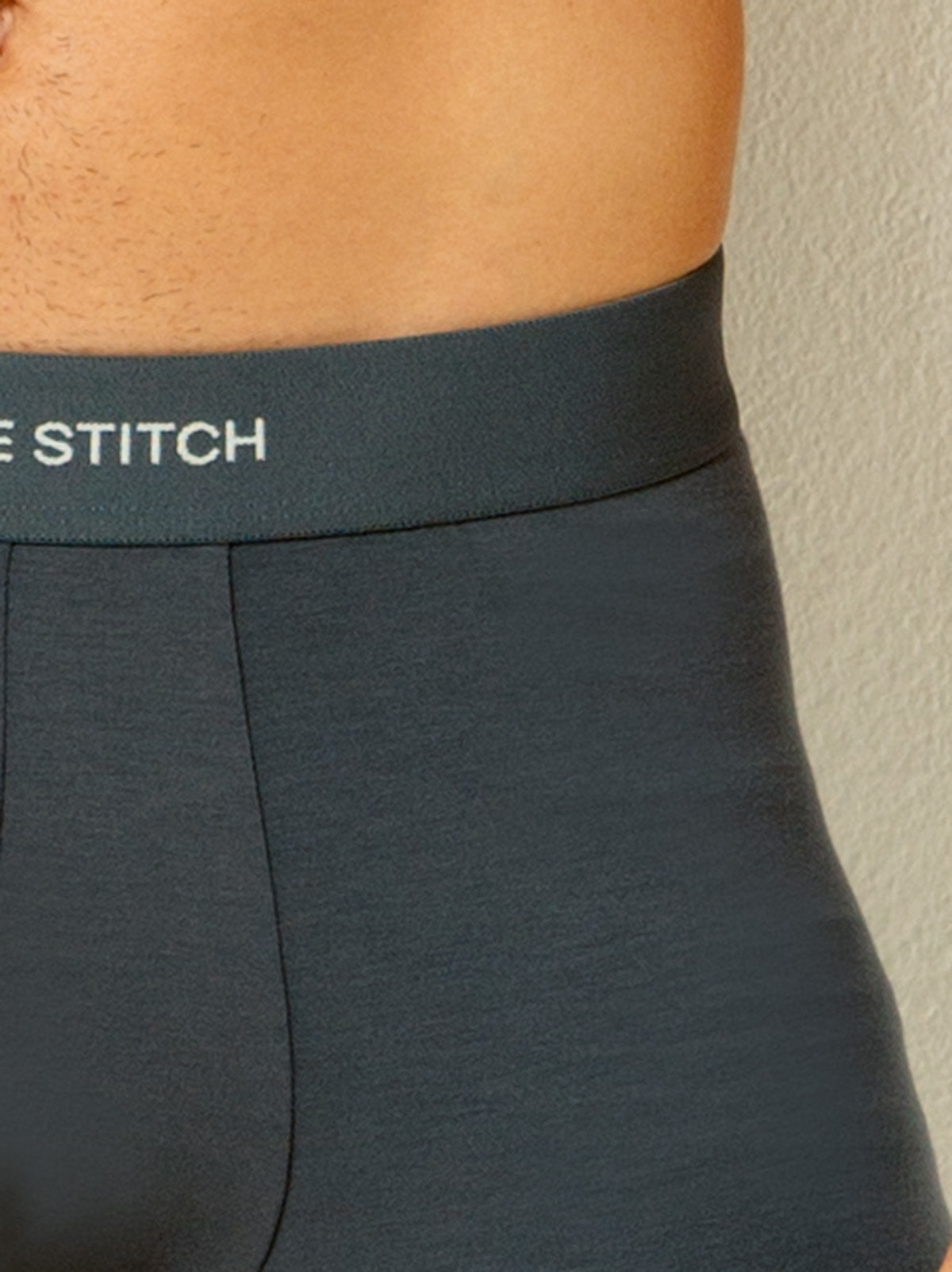 close up shot of male model wearing grey colored boxer briefs with single stitch logo on waist band